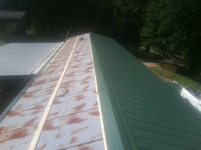 Old rusted panels beside newly installed green metal roofing — Wind Damage Roof Repair by Roofing Brothers in Aurora